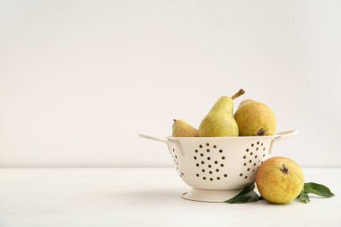 Beyaz zemin üzerinde olgun armutları olan Colander