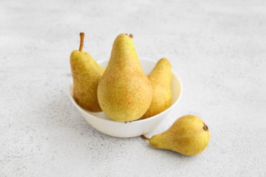 Beyaz arka planda olgun armutlarla dolu bir kase