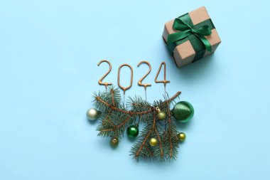 Noel topları, köknar dalları ve mavi arka plandaki hediye kutusundan yapılmış 2024 model.
