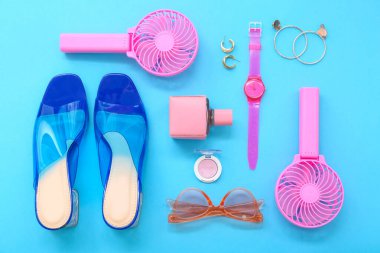 Mavi arka planda taşınabilir elektrikli fanlar ve şık bayan aksesuarları olan kompozisyon