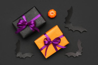 Cadılar Bayramı partisi için balkabaklı kağıt yarasalar ve siyah arka planda hediye kutuları.