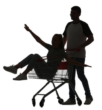 Beyaz arka planda, kız arkadaşıyla alışveriş arabasında genç bir adamın silueti.
