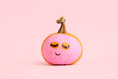 Pembe arka planda yüzü ve maskesi çizilmiş balkabağı
