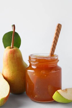 Cam kavanoz armut reçeli ve beyaz arka planda tahta kaşık.