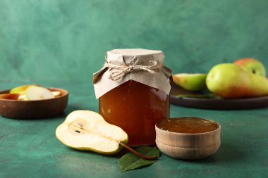 Cam kavanoz armut reçeli, ahşap kase ve grunge yeşil arka plan.