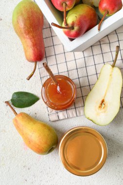 Cam kavanozlar dolusu armut reçeli ve beyaz masada sepet.