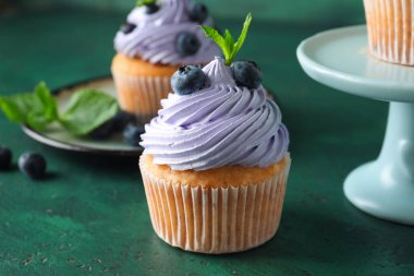 Yaban mersinli lezzetli kekler ve yeşil arkaplanda nane şekeri.