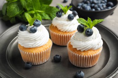 Gri arkaplanda yabanmersinli ve nane şekerli bir tabak lezzetli kek.