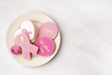 Pembe kurabiyeli tabak ve beyaz grunge arka planda gül çiçeği. Göğüs kanseri farkındalığı konsepti