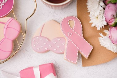 Kalp şeklinde kurabiyeler, sütyen ve beyaz grunge arka planda pembe kurdele. Göğüs kanseri farkındalığı konsepti