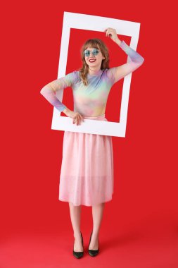 Kırmızı arka planda çerçeveli güneş gözlüklü genç bir kadın.