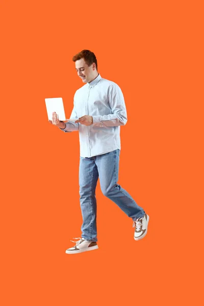 Skoky Mladý Muž Notebookem Oranžovém Pozadí — Stock fotografie
