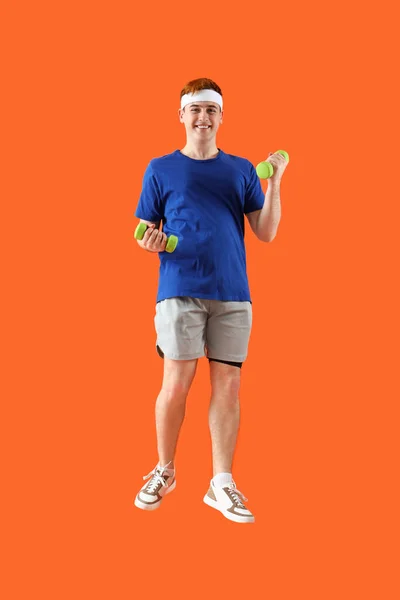 Sportlich Springender Junger Mann Mit Hanteln Auf Orangefarbenem Hintergrund — Stockfoto