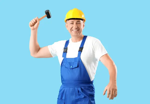 青い背景のハンマーが付いている成熟した労働者 労働者の日のお祝い — ストック写真