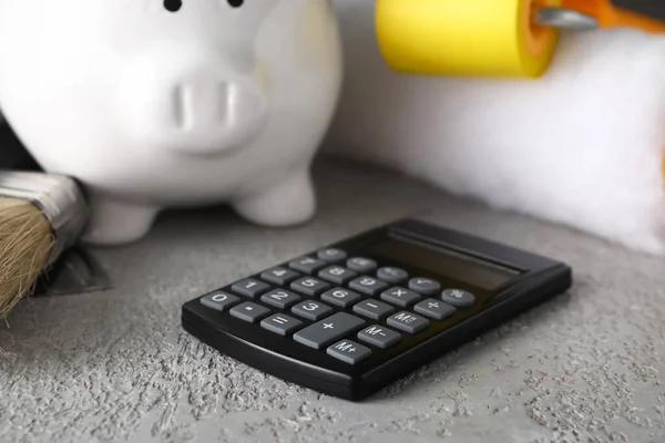Piggy Bank Calculator Paint Roller Grey Grunge Table Closeup Renovation — Stock Photo, Image