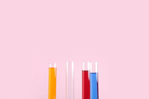 Test tubes with colorful samples on pink background, closeup