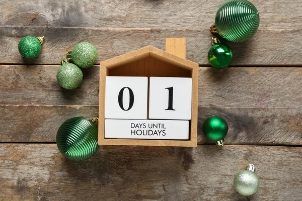 Countdown calendar with Christmas balls on brown wooden background