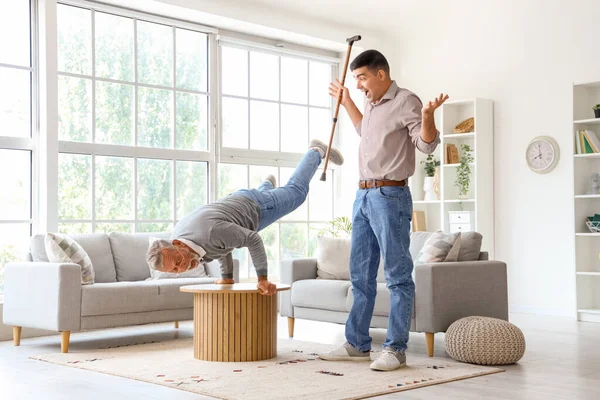 Surprised young man with stick and his father exercising at home