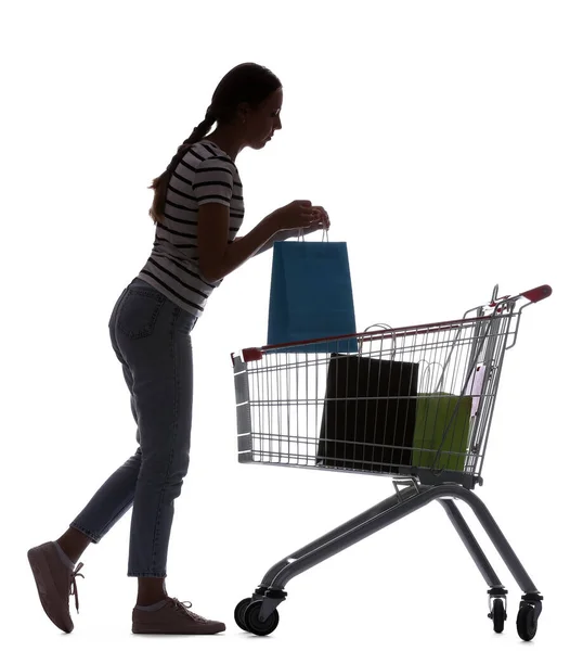 白い背景にバッグとショッピングカートを持つ若い女性のシルエット — ストック写真