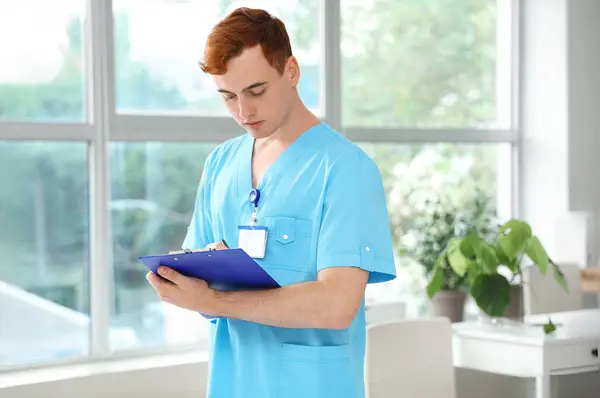 Male medical student with clipboard in clinic