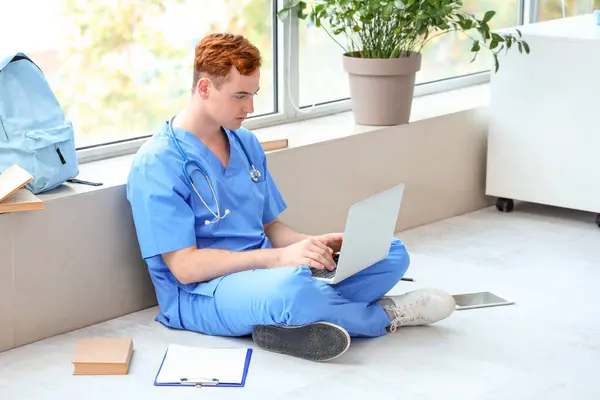 Male medical student studying with laptop at university