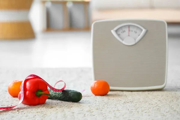 Scales with vegetables and measuring tape in living room. Weight loss concept