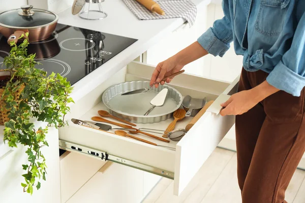 Woman putting spatula into kitchen drawer
