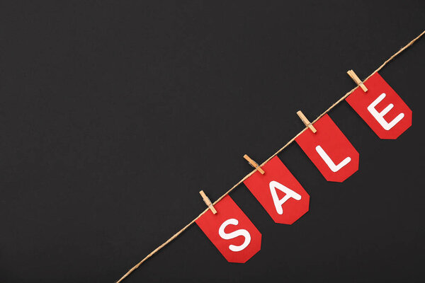 Верёвка, прищепки и флаги со словом SALE на чёрном фоне