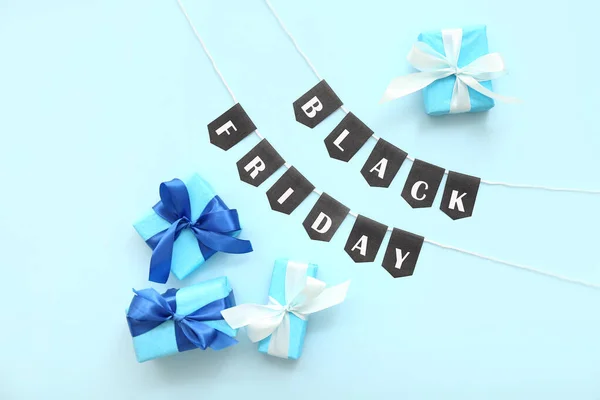 Gift boxes, rope and flags with text BLACK FRIDAY on blue background