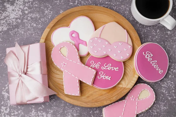 Cookies with pink ribbons and supportive words on grey background. Breast cancer awareness concept