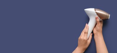 Mavi zemin üzerinde modern fotoepilatör ve metin için boşluk olan eller