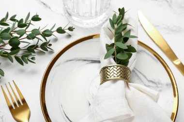 Katlanmış peçete ve grunge beyaz arka planda altın çatal bıçaklı tabak.