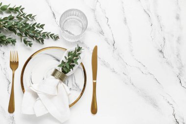 Katlanmış peçete ve grunge beyaz arka planda altın çatal bıçaklı tabak.