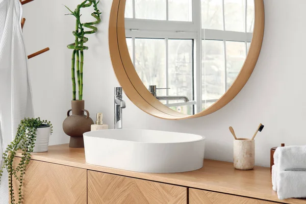 stock image White sink, bath accessories and vase with bamboo stems on table in room