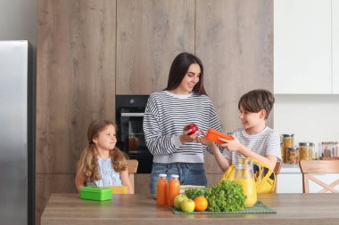 Anne küçük çocukları için mutfakta öğle yemeği hazırlıyor.