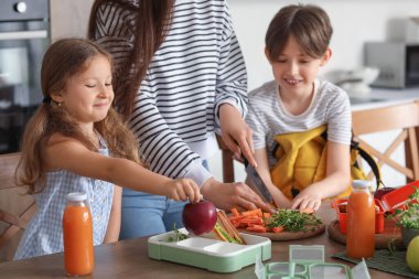 Anne, küçük çocuklarına mutfakta öğle yemeği hazırlıyor.
