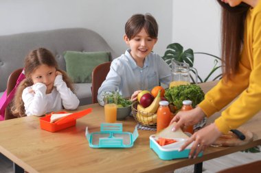 Anne küçük çocukları için mutfakta öğle yemeği hazırlıyor.