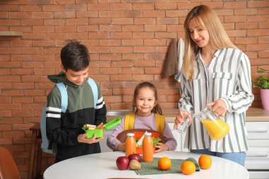 Okulda öğle yemeği yiyen küçük çocuklar ve anneleri mutfakta.