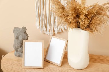 Blank frames, vase with pampas grass and decor on table in living room