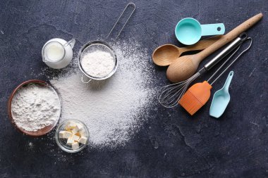 Koyu arkaplan üzerine fırın hazırlamak için malzemeler ve farklı çatal bıçaklar içeren kompozisyon