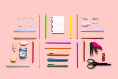 Pembe arka planda farklı kırtasiye malzemesi içeren defter.