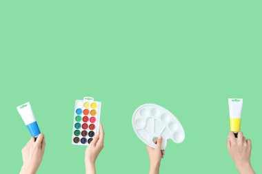 Yeşil arka planda sanatçı malzemeleri olan kadın eller.