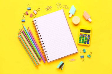 Sarı arka planda farklı kırtasiye malzemesi içeren defter