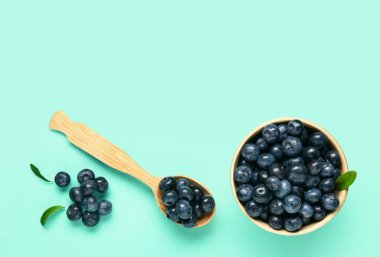 Ahşap kaşık ve kase mavi arka planda taze yaban mersini.