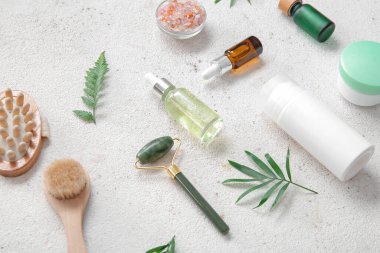 Kozmetik ürünleri ve hafif arka planda fırçaları olan taş yüzlü masaj silindiri.