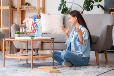 Dizüstü bilgisayarı olan genç bir kadın evde İngilizce öğreniyor.