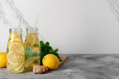 Gri masada zencefilli ve naneli limonata şişeleri.