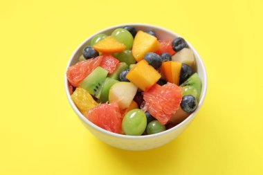 Sarı arka planda taze meyve salatası.