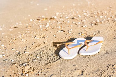 Havalı kadın terliklerini kuma atıyor.