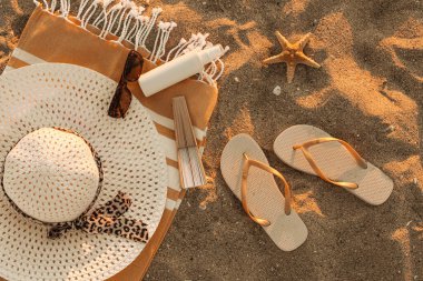 Havalı kadın terlikleri ve kumsaldaki aksesuarlar.